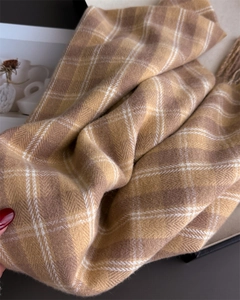 Gros plan d'une écharpe à carreaux jaune et beige montrant la texture douce et franges