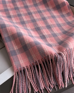 Détail d'une écharpe douce à carreaux rose gris blanc avec des bords à franges