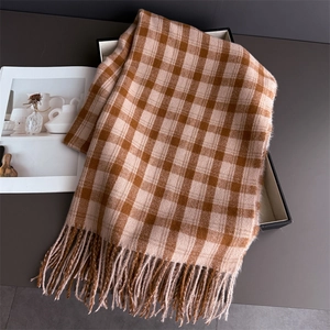 Détail d'écharpe à carreaux avec franges sur boîte cadeau à côté d'un magazine