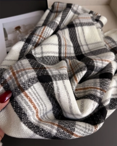 Close-up of thick plaid scarf fabric showing soft cashmere-like texture and tassels