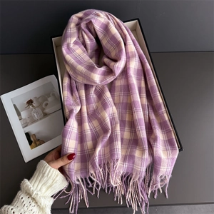 Gros plan sur l'écharpe à carreaux violet et beige avec franges dans un coffret