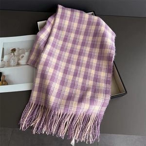 Détail d'une écharpe à carreaux violet et crème avec des franges dans un coffret cadeau