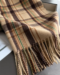 Close-up of soft plaid scarf fabric with tassel fringe in warm beige and brown tones