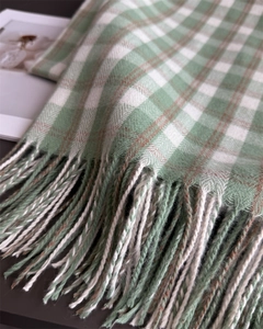 Détail d'une écharpe à carreaux verts et blancs avec tissage à chevrons et franges