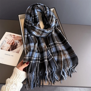 Detail shot of the blue and black plaid scarf with fringe in a luxury gift box