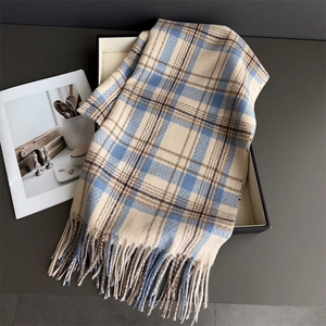 Close-up of blue and beige plaid scarf with soft fringe texture on a display tray