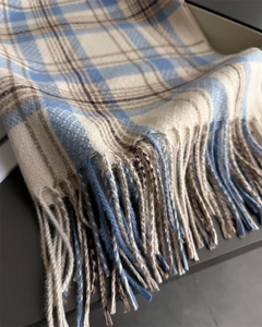 Detail of soft sky blue and cream plaid scarf with fringe texture and high-quality weave