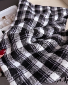 Gros plan sur la texture de l'écharpe à carreaux avec pompons et toucher doux cachemire