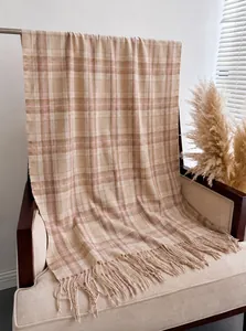 Detail of British plaid cashmere-like scarf with fringe on a cozy cream sofa