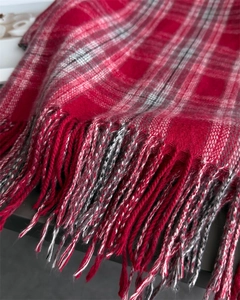 Close-up of red and black tartan scarf texture with detailed fringe and soft wool-like finish
