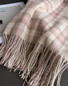 Close-up of soft cashmere-feel plaid scarf with delicate fringe and beige-pink patterns