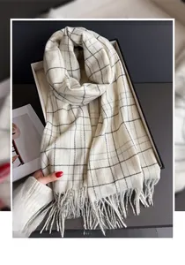 Macro detail of beige cashmere-like scarf featuring black plaid patterns and fringe edges