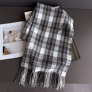 Macro shot of neutral plaid cashmere-feel scarf with tassels in a premium display box