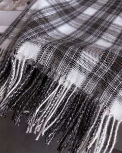 Close-up of classic plaid scarf featuring black, white, and brown patterns with long fringe