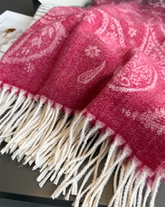 Detailed close-up of pink paisley scarf with intricate white floral patterns and tassels