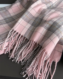Detail of soft pink plaid scarf featuring classic check patterns and fringe tassels