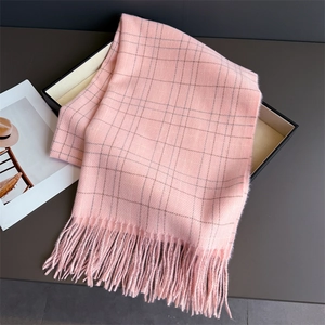 Close-up of a light pink plaid cashmere scarf with soft fringes in a grey gift box
