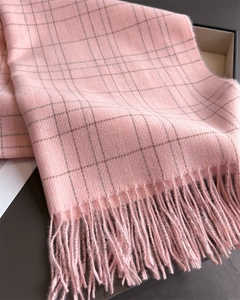 Close-up of pink plaid scarf texture showing soft cashmere-like fabric and elegant tassels