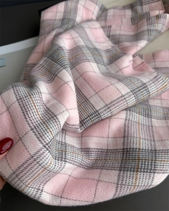 Close-up of soft cashmere-feel fabric with pink and grey plaid pattern and fringe details