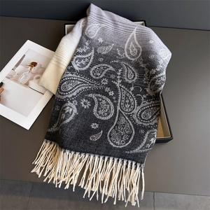 Detail of paisley pattern and long tassels on a grey gradient cashmere scarf