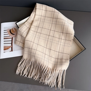 Close-up of beige plaid scarf fringe texture and premium gift box presentation