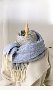 Detailed view of the 100% imitation cashmere scarf with tassels on a white coat