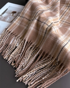 Close-up of classic earthy plaid pattern and soft tassel edges on the winter scarf