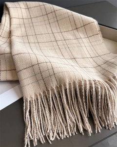 Macro detail of plaid cashmere scarf showing soft fiber texture and tassel fringe edges