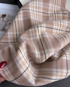 Close-up of British plaid scarf fabric showing soft cashmere-like texture and tassel detail