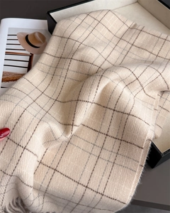 Detailed view of beige plaid scarf showing soft cashmere-like texture and tassel fringe