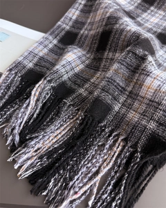 Close-up of thick British plaid fabric with delicate long tassels on the scarf edge