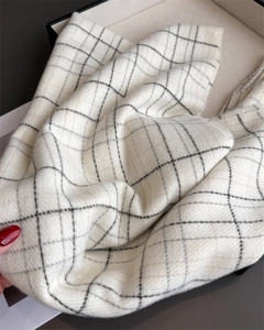Close-up of beige plaid scarf showing soft cashmere texture and delicate fringe edge