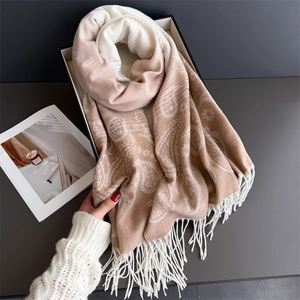 Detail of warm paisley cashmere-like scarf with tassels and soft beige color gradients