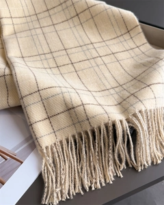 Close-up of beige plaid scarf featuring soft cashmere-like texture and long tassel details