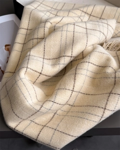 Close-up of beige plaid scarf showing soft twill weave texture and elegant fringe details