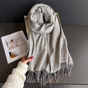 Detail shot of classic grey plaid scarf showing soft tassels and thick knit texture