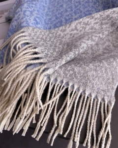 Close-up of soft tassel edges and jacquard texture on light blue cashmere-feel scarf