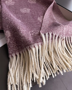 Detailed close-up of dark burgundy camellia knit shawl featuring long cream fringe tassels