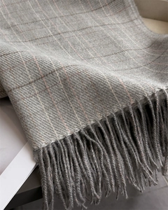 Close-up of gray plaid cashmere scarf with soft pink stripes and long fringe details