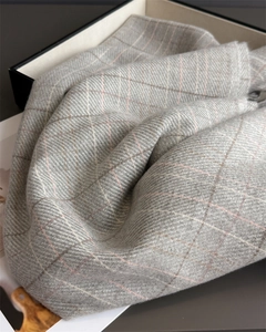 Detail of plaid cashmere-feel scarf with tassels and elegant gift box packaging