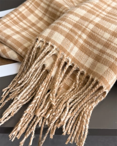 Detailed close-up of camel plaid scarf fringes and soft cashmere-like texture fabric