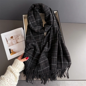 Detailed close-up of plaid cashmere-like scarf texture with elegant hanging tassels