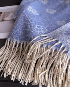 Close-up of soft blue camellia pattern scarf showing tassel edges and cashmere texture