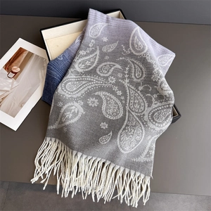 Detail of paisley pattern on soft cashmere-like scarf with fringe edges in grey and blue