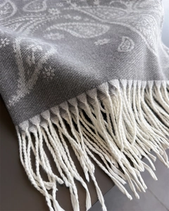 Macro shot of grey paisley cashmere scarf detailing soft texture and white fringe tassels