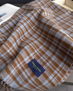 Detail of soft plaid scarf fabric with elegant brand label and fringe texture