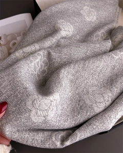 Close-up of luxury grey camellia jacquard scarf showing soft texture and tassel details