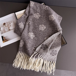 Macro detail of the elegant camellia floral pattern and dense fringe on a luxury scarf