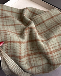 Macro view of light bean green and brown plaid fabric texture and soft fringe details