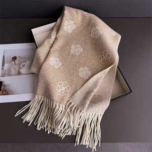 Detail of beige cashmere scarf featuring white camellia flower patterns and fringe edges
